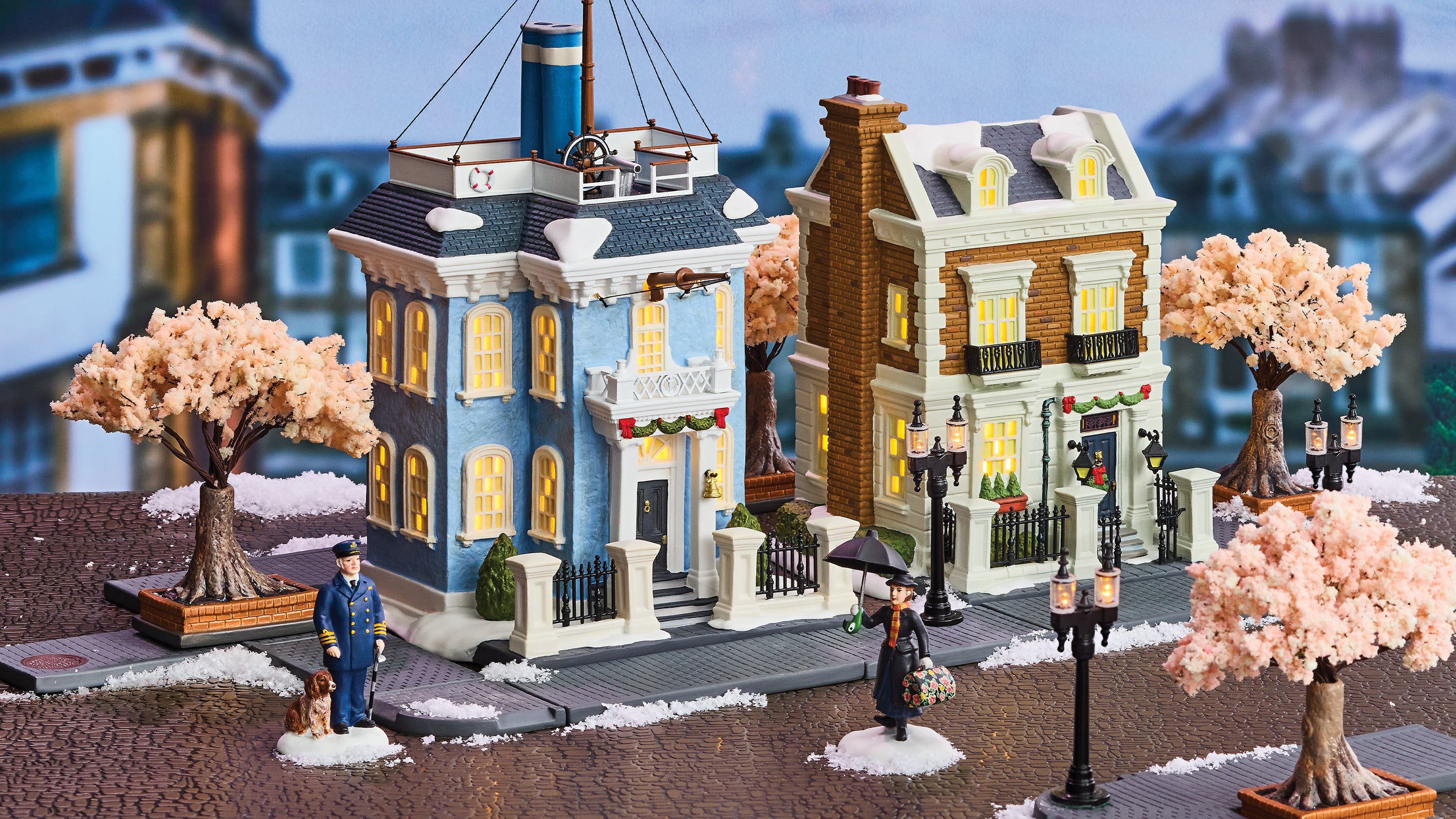 Model of a snowy street scene with buildings, trees, and people in a miniature town setting.