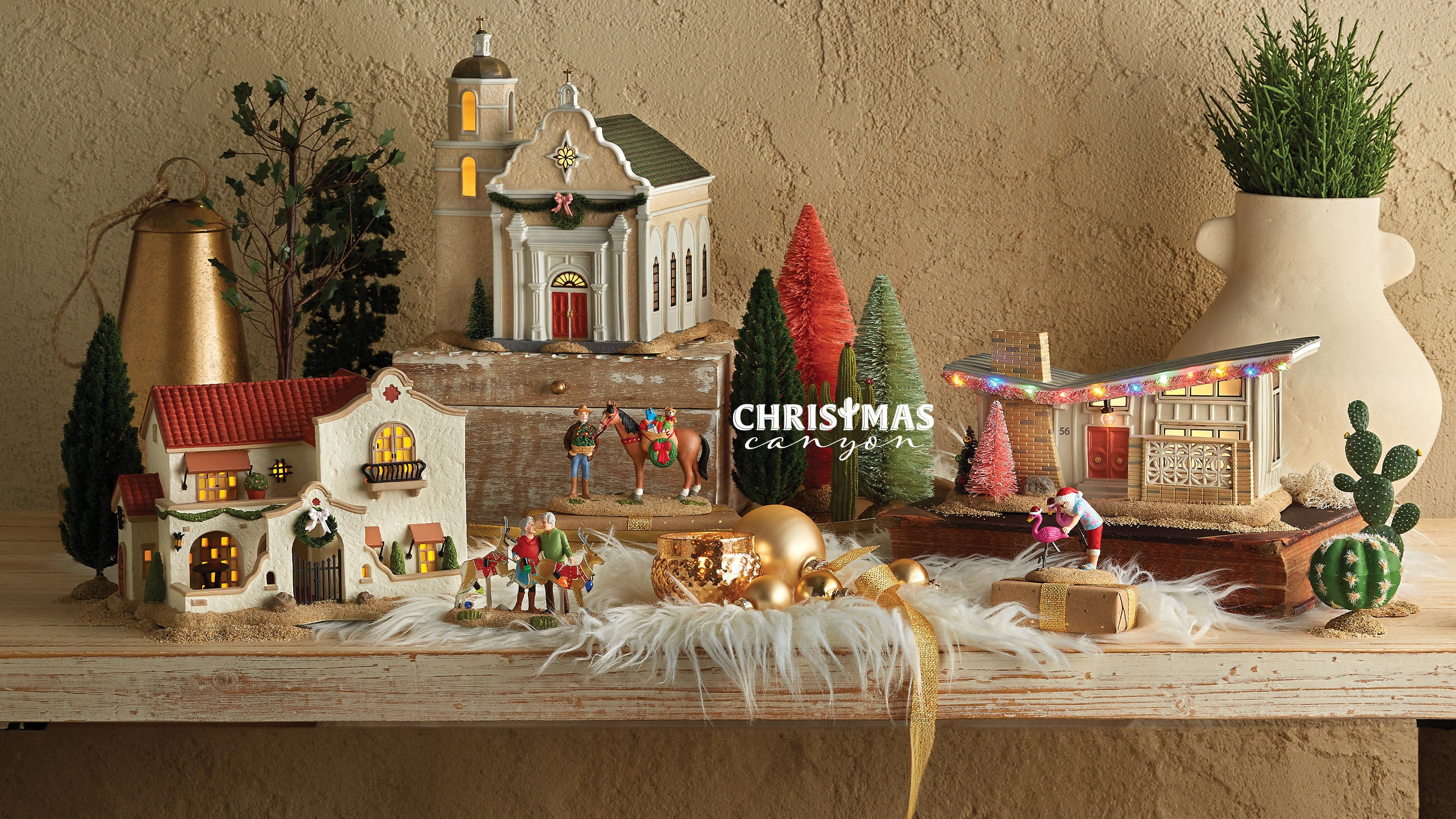 Christmas-themed diorama with miniature houses, trees, and figures on a wooden surface.