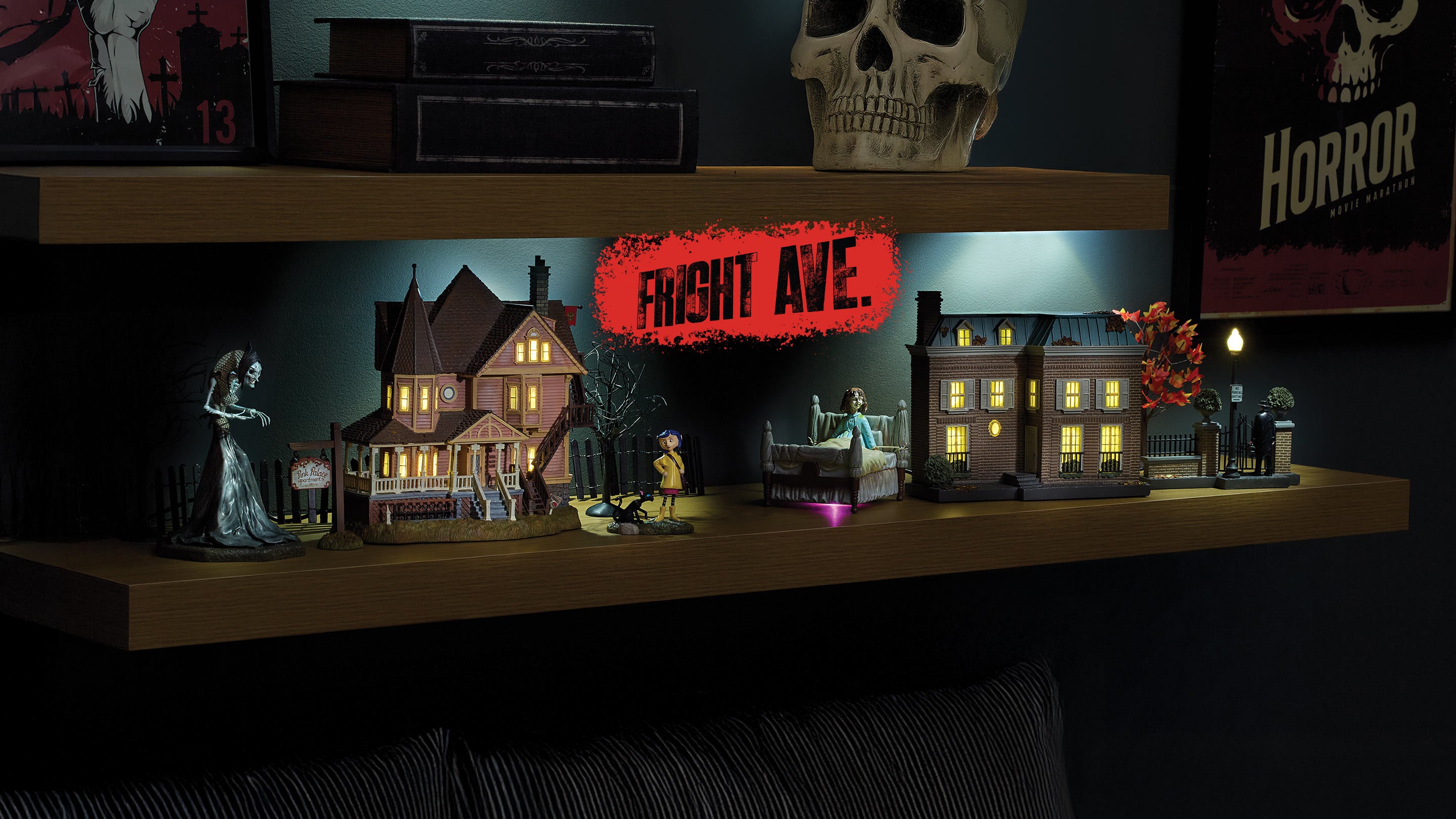 Horror-themed decorative shelf with model houses, figures, and a skull.