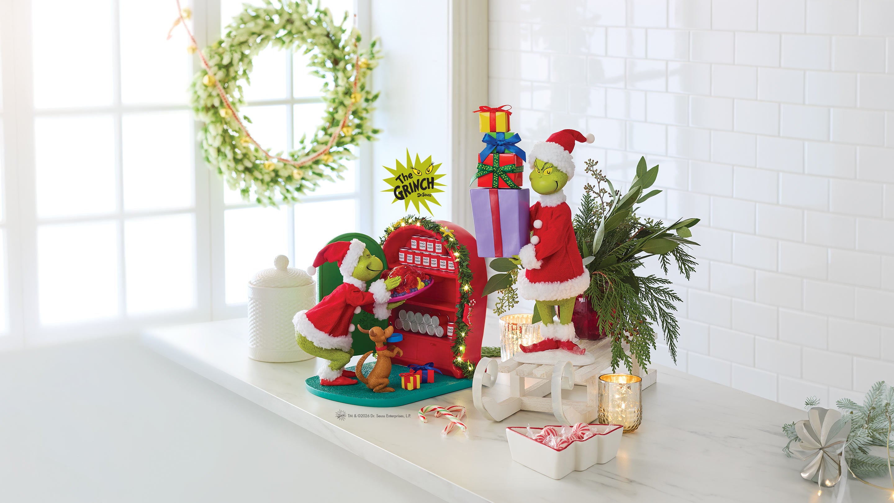 Decorative Christmas scene with Grinch figures and festive elements on a white surface.