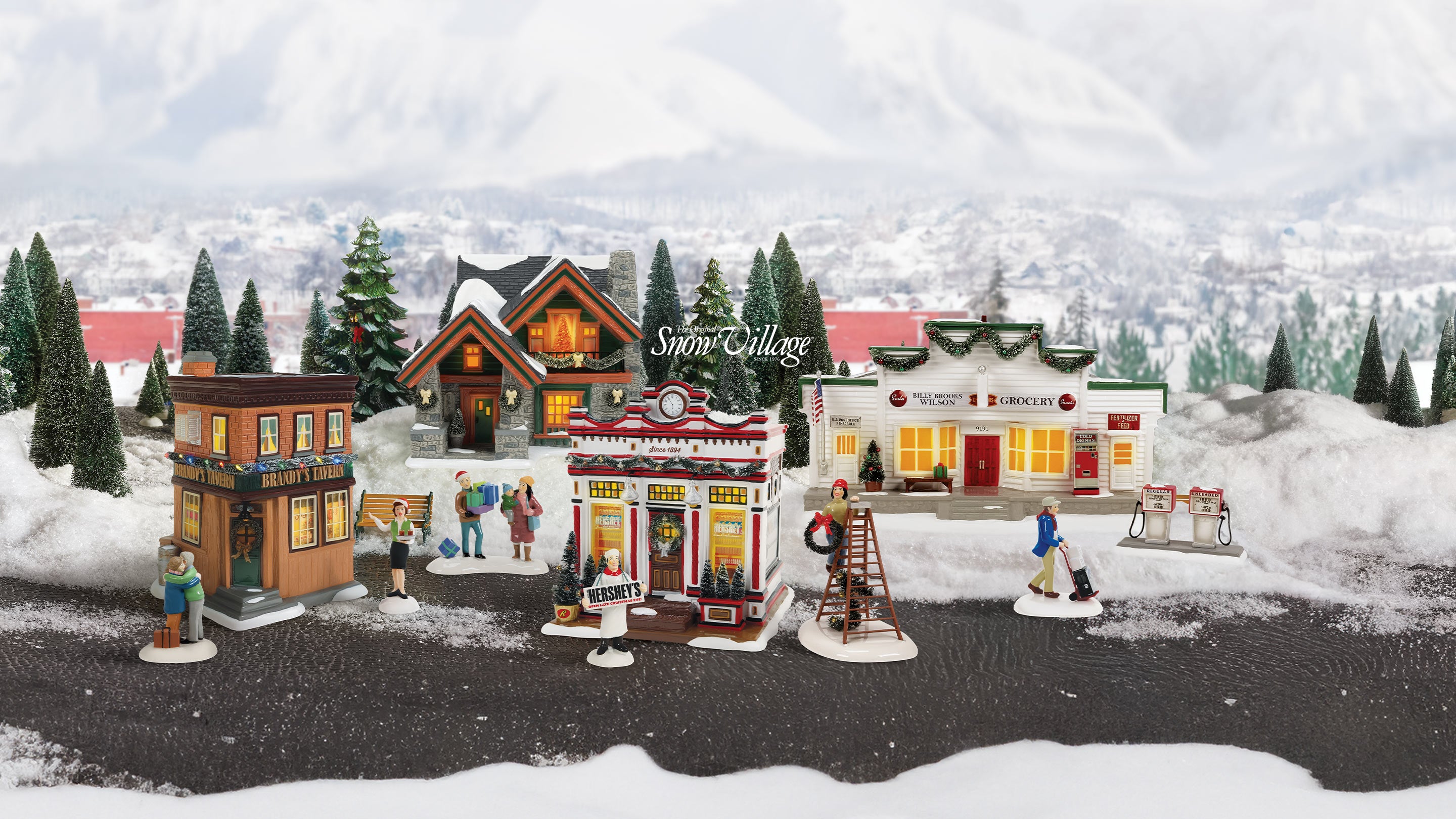 Model village scene with buildings and figures in a snowy landscape