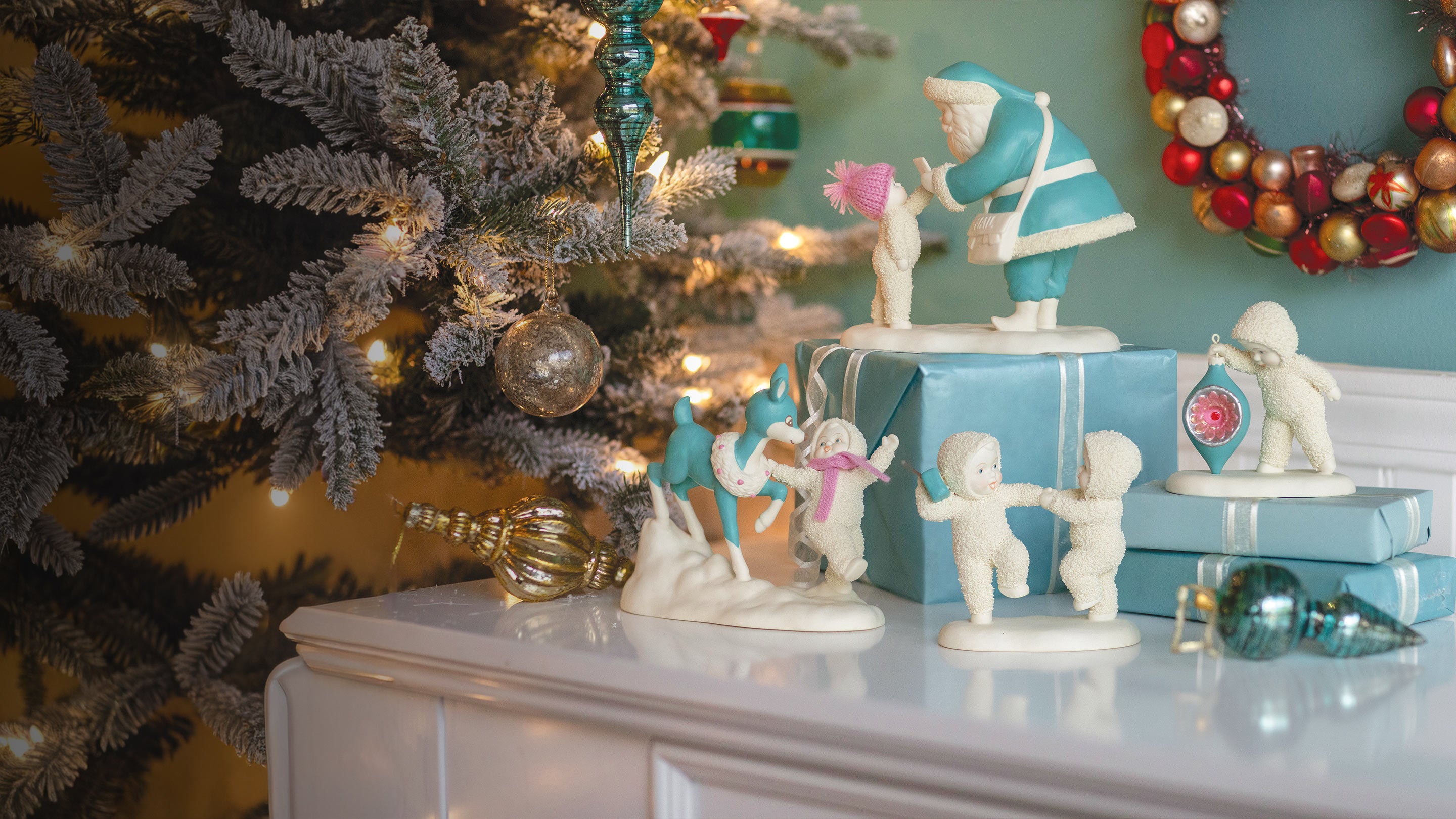 Decorative Christmas scene with figurines, a tree, and ornaments on a mantelpiece.