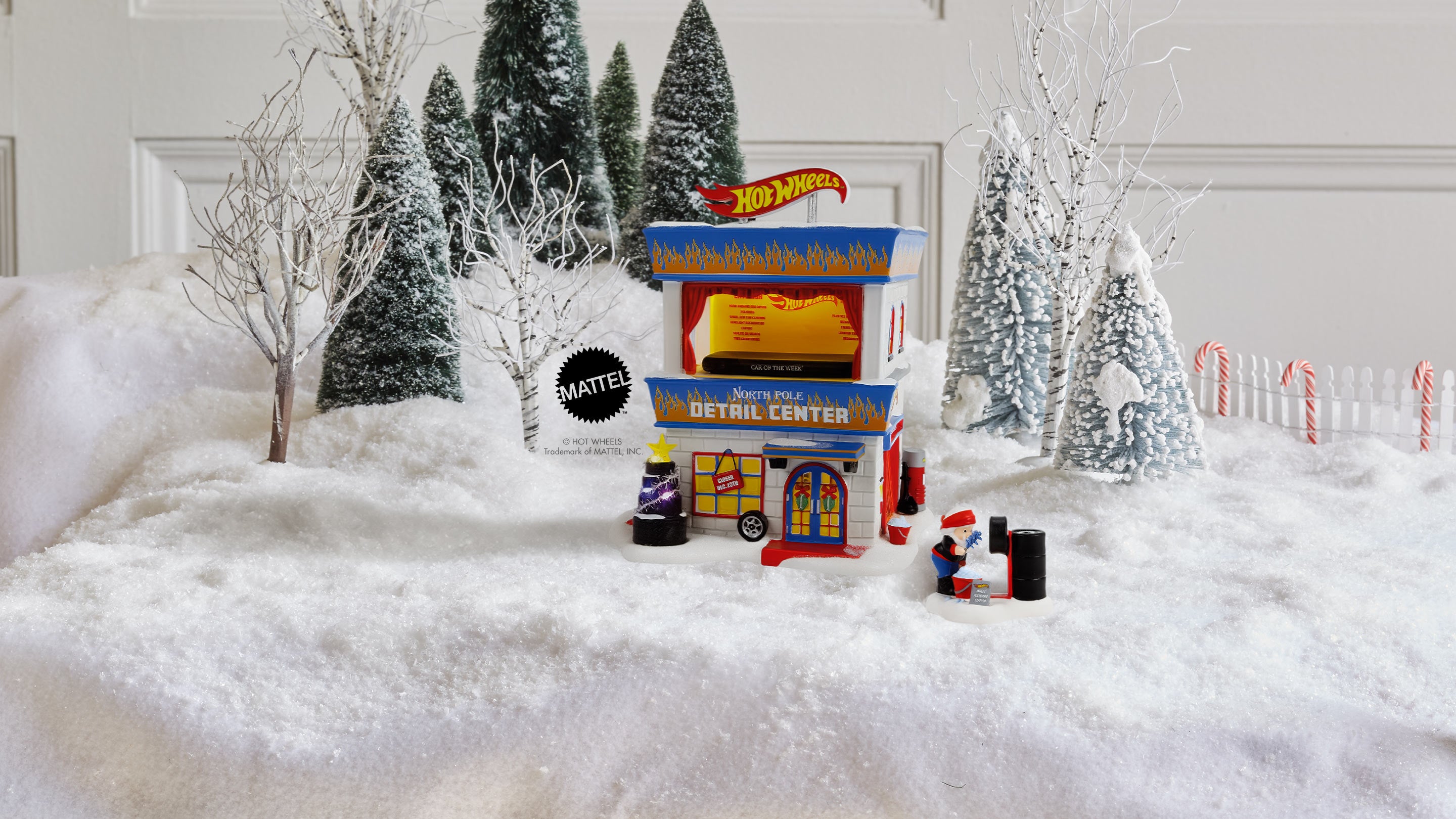 Hot Wheels Detour Center toy building displayed in a snowy diorama with miniature trees, snow-covered Christmas trees, and small figures on a white surface.