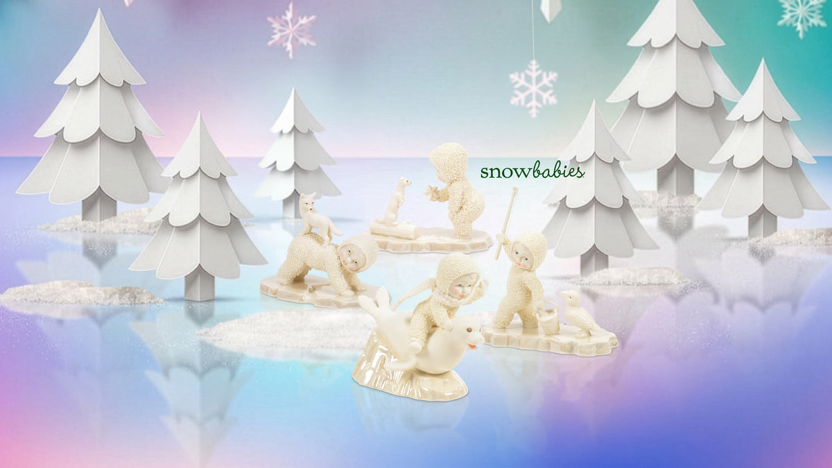 A collection of small cream-colored snowman figurines posed in a stylized winter scene with white paper trees and snowflakes on a pastel blue and purple gradient background. The text 'snowbabies' is visible near the center.